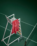 Tennis racket leaning against a stand with red towels on a tennis court